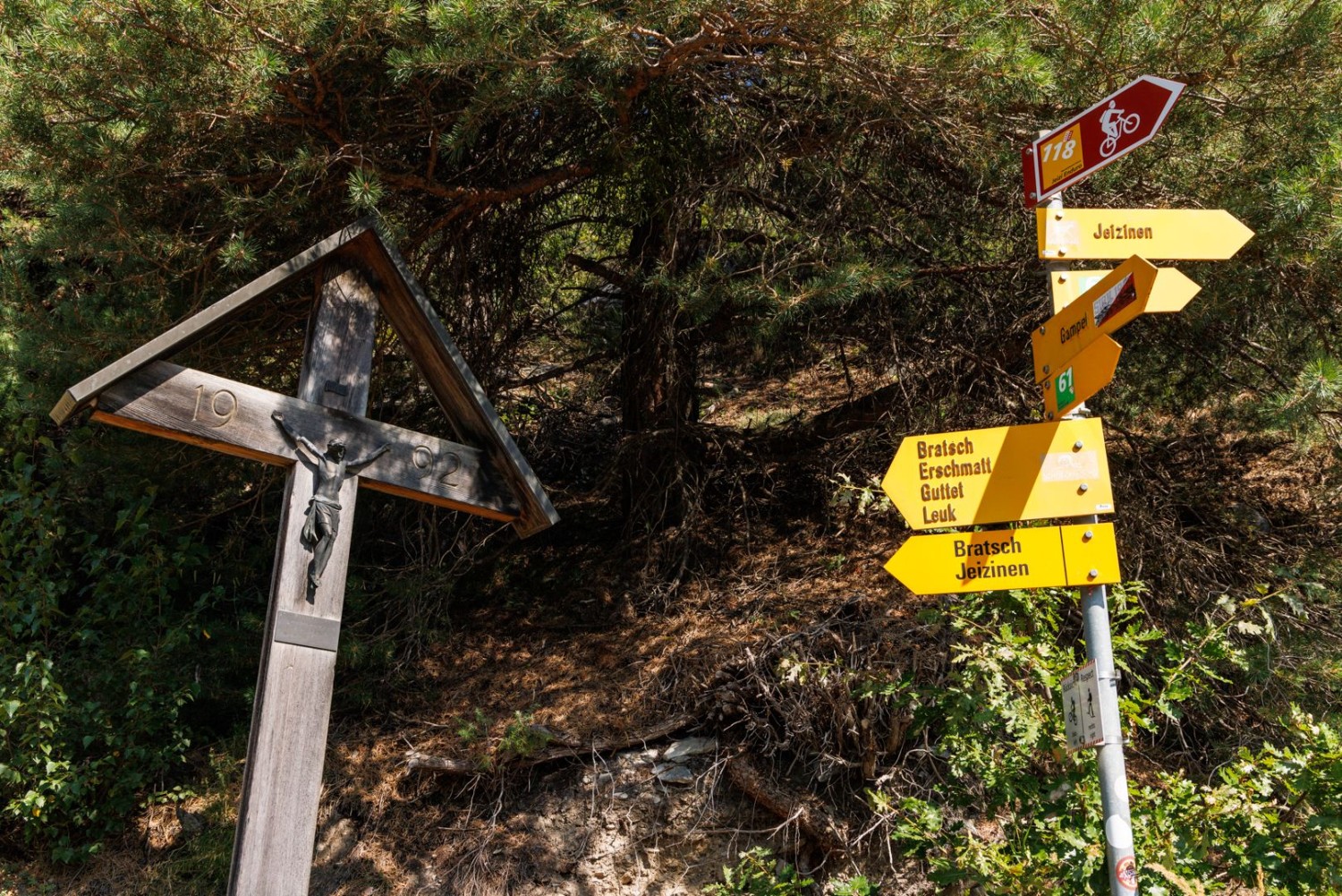 Wegweiser und Wegkreuze begleiten Wandernde beim Aufstieg.